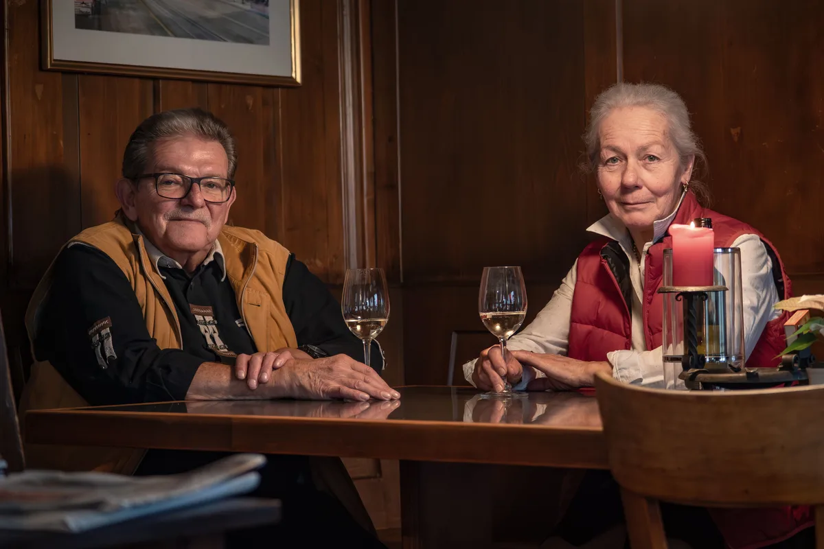Ein Mann und eine Frau mit Weinglas an einem Tisch.